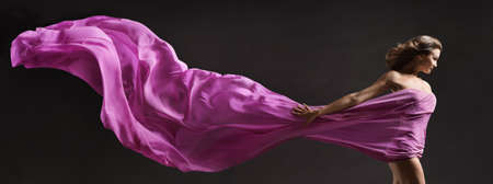 Woman dancing. Modern Ballet Dancer with long Fabric Banner flying on Wind in Air. Copy Space. Black Backgroundの写真素材