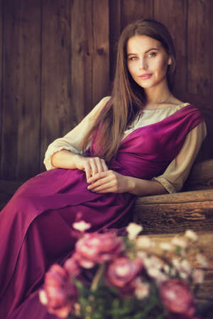 Vintage Woman Portrait blossom Flower in Basket. Beauty Model happy smiling over dark Wooden Background Pink Dressの写真素材