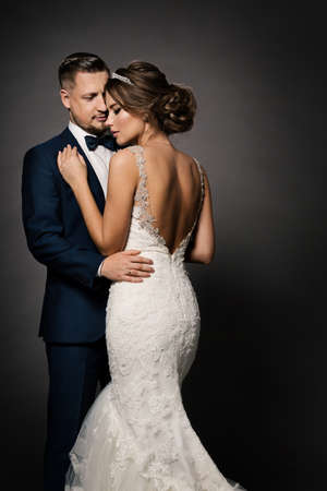 Wedding Couple Fashion Portrait. Bride Back view and Groom embracing Woman. Black Studio Backgroundの写真素材