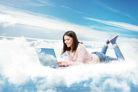 Woman using Laptop on Cloud. Happy Young Girl typing on Computer Lying Down. Cloud Technology Internet Information Data Concept. Online E Learning Studyの写真素材