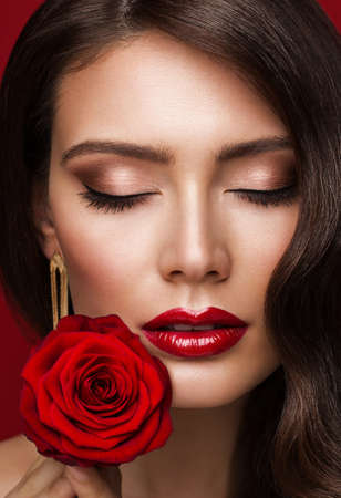 Woman Red Lips with Rose Flower. Beauty Model Face Makeup with Closed Eyes. Fashion Brunette Girl Close up Portrait over Red Backgroundの写真素材