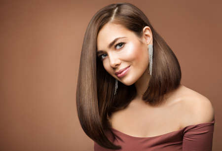 Woman Long Bob Haircut. Smiling Beauty Model with Brown Shiny Straight Hairstyle looking at Camera over brown Backgroundの写真素材