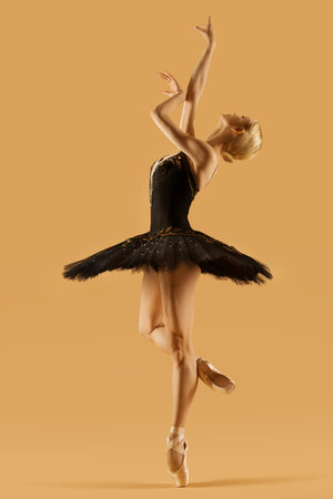 Ballerina Dancing in Classic Tutu Skirt. Ballet Dancer in Black Dress Balance at One Leg over Beige...
