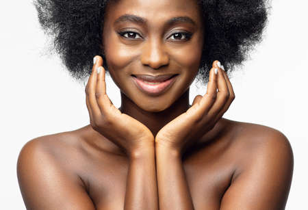 Black Woman Beauty Face. Happy Afro American Model Portrait with Curly Natural Hair and Shiny Full Lips over White Studio Background. Dark Skin Care and Cosmeticsの写真素材