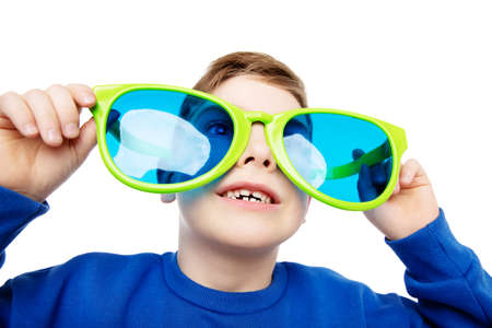 Funny Child in Big Eyeglasses smiling and looking up. Happy Little Boy in Glasses laughing over White Background. Curious Schoolboy in large Spectacles excitedの写真素材