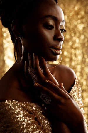 African Beauty Woman with Gold Jewelry over shining Background. Dark Skinned Model with Golden Lips...