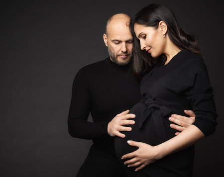 Happy Pregnant Couple looking at Belly. Mother and Father Love expecting Baby during Pregnancy....