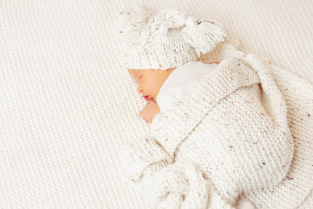Newborn Sleeping on Stomach. Cute Baby in knitted Hat covered with Woolen Blanket. Infant Child sleep lying down on White Bed. New born Boy dreamingの写真素材