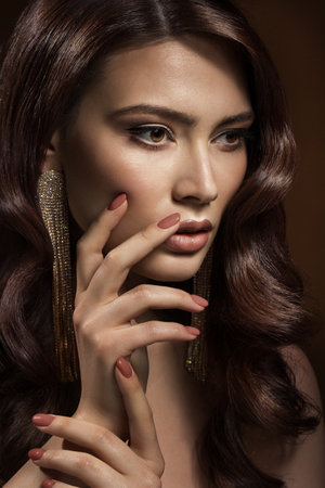 Beauty Woman Nails Manicure. Brunette Model with Holiday Make up and Curly Hairstyle. Women Natural Lips Makeup Portrait over Brown Backgroundの写真素材