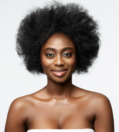 Dark Skin Model with Afro Hairstyle. Smiling African Beauty Woman with Natural Face Skin Make up over White studio Backgroundの写真素材
