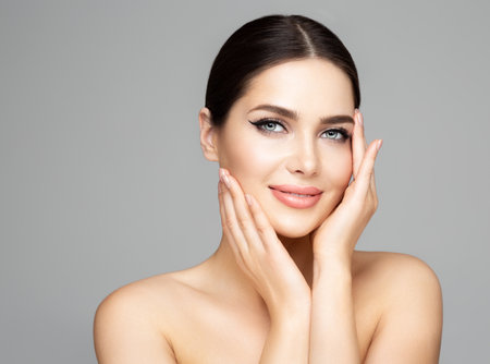Face Skin Care. Beauty Woman with Full Lips Natural Makeup over Gray. Beautiful Model Facial Massage. Facelift Plastic Surgery and Dermal Filler Cosmetologyの写真素材