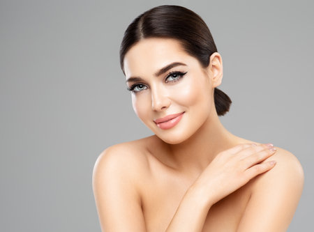 Beauty Woman. Beautiful Girl with perfect natural Makeup. Happy Model Portrait over Gray. Women Smooth Face Skin and Body Care. Spa Cosmetologyの写真素材