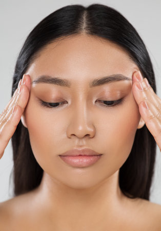 Beauty Woman Closeup Face Lift Massage. Beautiful Asian Model Portrait with Natural Make up. Women Facial Dermal Filler. Eyes Care Cosmetology and Plastic Surgeryの写真素材
