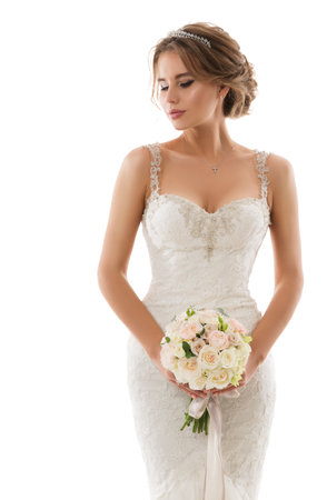 Bride in Wedding White Dress with Flower Bouquet. Beautiful Woman in Bridal Gown with Evening Hairstyle and Perfect Makeup over isolated backgroundの写真素材