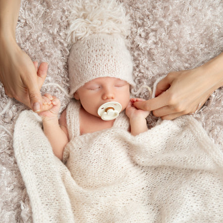 Newborn sucking Pacifier in Sleep. Parent holding Baby Fist in Hands. One Month little Child with...