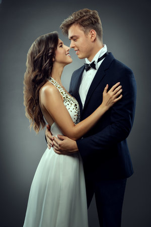 Wedding Couple in Love looking at each other side view. Romantic Bride and Groom Happy embracing. Smiling Elegant Man and Lady over Gray Backgroundの写真素材