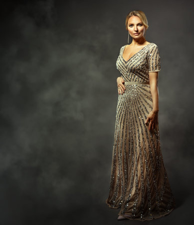 Elegant Lady in Long Glitter Dress. Fashion Adult Woman in Evening Sequin Gown over dark Background....