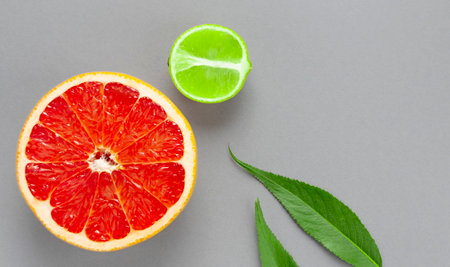 Half a grapefruit and lime with green leaves on the table on a gray background with a copy space. view from above. food minimalism.の写真素材