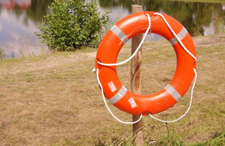 Orange lifebuoy on a post at the waterfront of a poolの写真素材