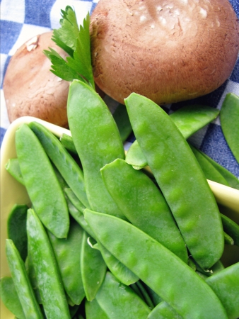 Edible podded peas and mushrooms at a dish towelの写真素材