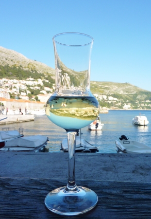 A glass of white wine withe reflections of Dubrovnik in Croatiaの写真素材