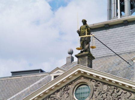 A statue of lady justice with the sword and the balance scales on the historical city hall in the center of the city Vlaardingen in the Netherlandsの写真素材