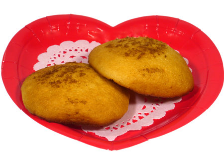 Golden yellow baked Dutch egg cakes on a red heart over white