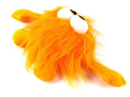 Orange toy monster with long hair and bulging eyes as a soccer mascot over whiteの写真素材