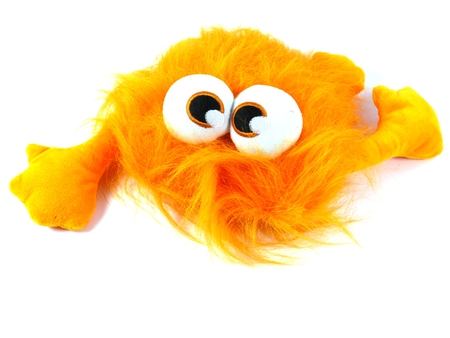 Orange toy monster with long hair and bulging eyes as a soccer mascot over whiteの写真素材