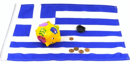 An empty piggy bank on the Greek flag with small euro coinsの写真素材