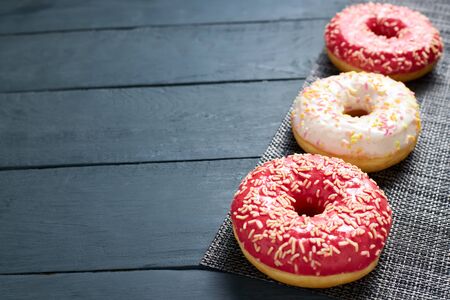 Colorful glazed donuts on dark wooden background.の写真素材