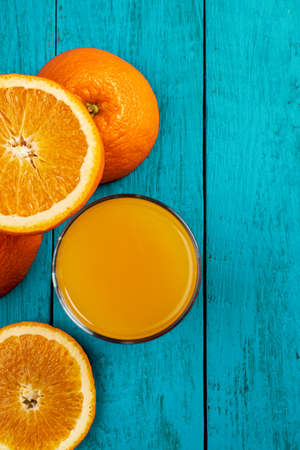 Glass of orange juice on wooden table with fresh sliced fruits of orange. Top view.の写真素材