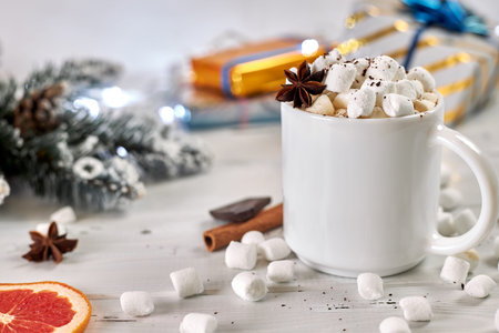 Mug of hot coffee with marshmallows sprinkled with chocolate, anise, cinnamon and a slice of dried...