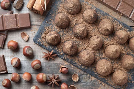 Homemade chocolate truffles sprinkled with cocoa powder and assorted chocolate with nuts and other spices on rustic old kitchen table. Top view.の写真素材