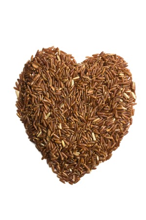 Red rice in heart shaped  on whiteの写真素材