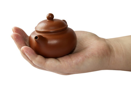 Chinese teapot in hand closeup on white backgroundの写真素材