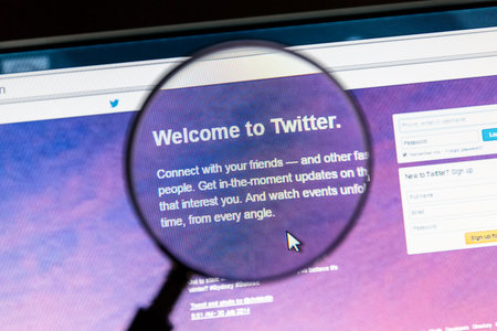 Twitter's website under a magnifying glass. Twitter is an online social networking service that...