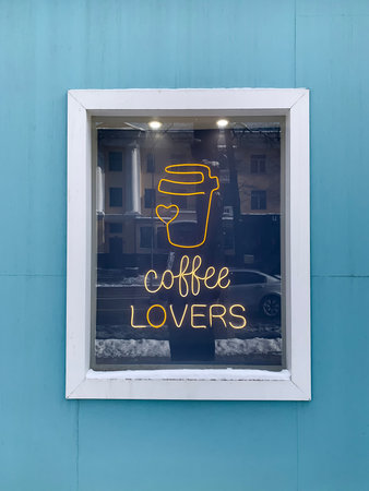 Neon lettering Coffee lovers on cafe window, mobile photo.