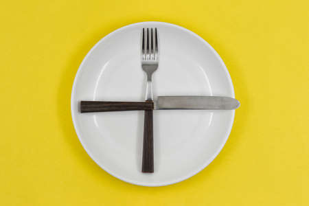 White empty plate with fork and knife on yellow backgroundの写真素材