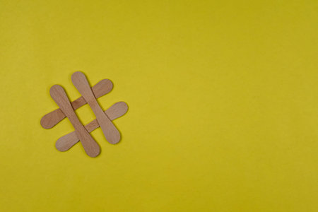 Hash tag symbol made from wooden sticks on blue paper background with copy space for text