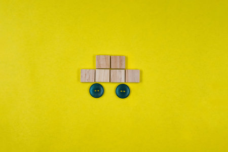 Silhouette of a car made of wooden dice on yellow paper background