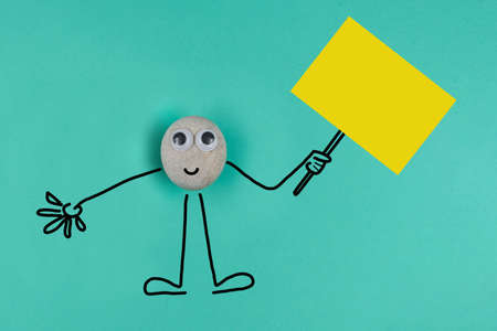 Animated pebble with a happy face holds big memo on blue paper backgroundの写真素材