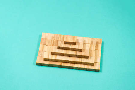 A pyramid stacked with wooden blocks on a blue paper backgroundの写真素材
