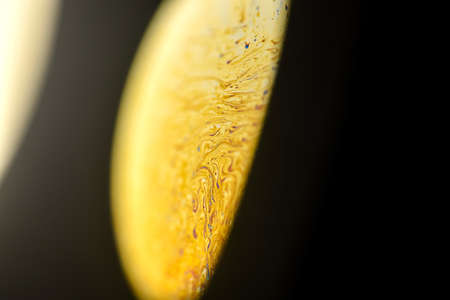 Closeup abstract soap bubble, like rotating off the fully illuminated by a satellite yellow alien planet in universe on dark backgroundの写真素材