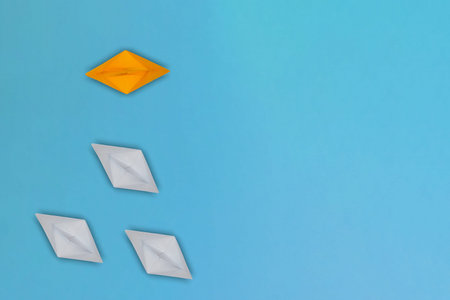 White paper boats going in the wrong direction, one yellow boat going in the right direction....