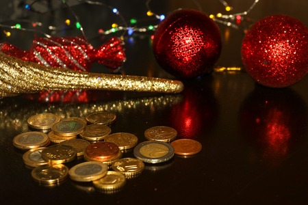 Bunch of euro coins on black background with blurred reflection of glitter christmas toys balls, candy and icicle for have luck, success and good finance fortune in next new yearの写真素材