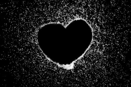 Empty love heart symbol drawing by finger on white salt powder on black background. Romantic St. Valentines Day holidays concept with place for text. Copy space.の写真素材