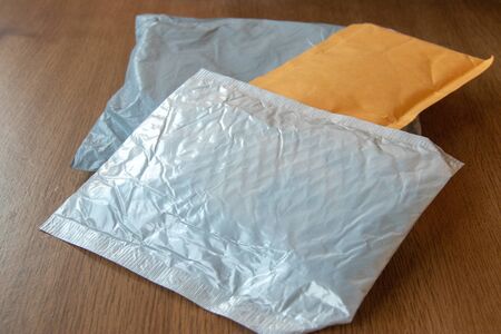 Three postal parcels small package white, gray and yellow lay on wooden background surfaceの写真素材