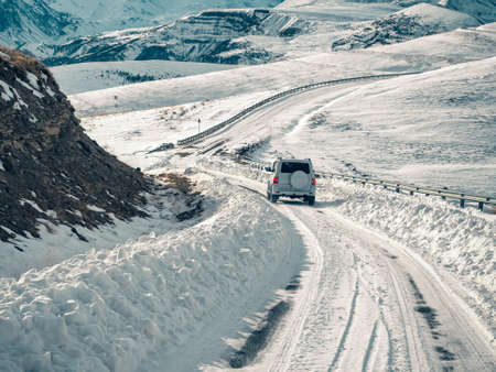 The SUV is moving along a winter road in the mountains. The concept of auto travel.の写真素材