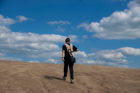 The young man walks towards the horizon up a gentle slope. The concept of lifting.